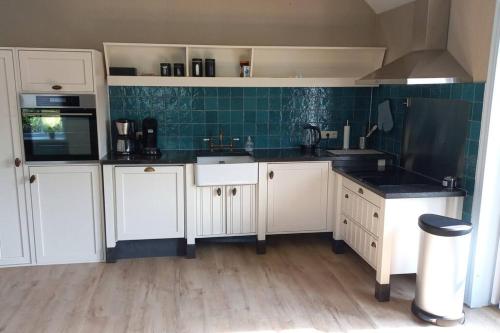 a kitchen with white cabinets and black counter tops at Slapen in een eeuwen oude Pastorie 