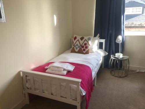 a bedroom with a bed with pink sheets and a window at Luxury Town Centre Property with parking in Cheltenham