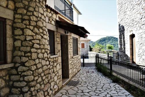 a stone building with a fence next to a street at Stonehouse dome Lagadia in Lagadia
