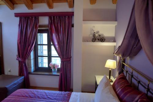 a bedroom with a bed and a window with purple curtains at Archontiko Deligianni in Dhimitsana