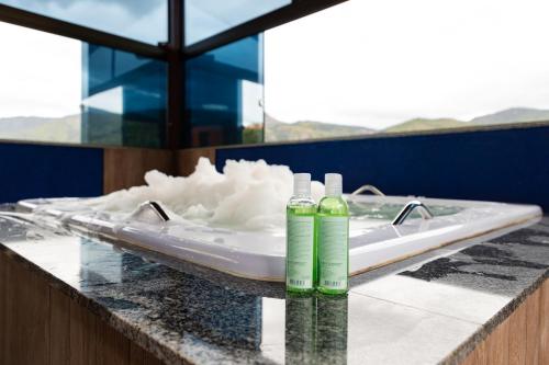 2 botellas verdes encima de una bañera en Estâncias da Serra dos Alves 2, en Itabira