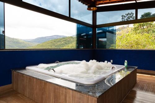 a bath tub with white foam in a room with mountains at Estâncias da Serra dos Alves 2 in Itabira