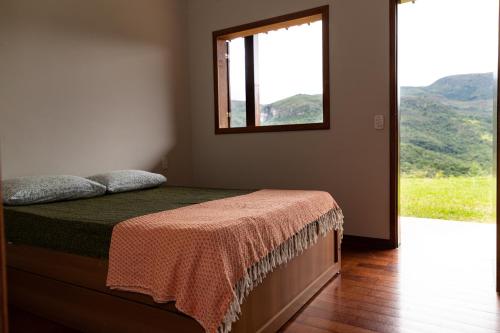 Schlafzimmer mit einem Bett und einem Fenster mit Aussicht in der Unterkunft Estâncias da Serra dos Alves 2 in Itabira