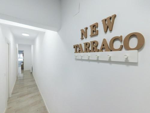 un corridoio bianco con un nuovo segno di taraca su un muro di Apartamento New Tarraco a Tarragona