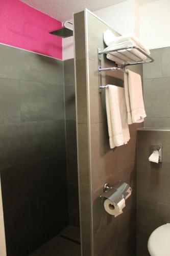 a bathroom with a shower with a toilet and towels at Enzo Hôtels Premier Prix - Logis Amnéville in Amnéville