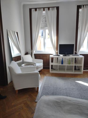 a living room with two white chairs and a television at Trappelgasse Top 26 in Vienna