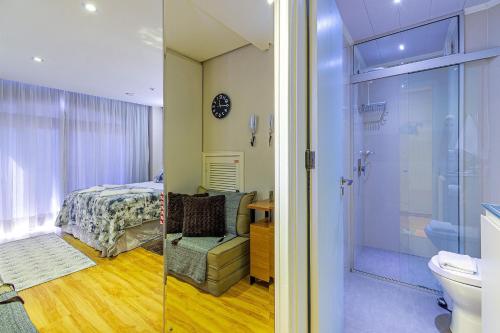a bedroom with a bed and a bathroom with a shower at No centro de Canela - @stayhousetemporada in Canela