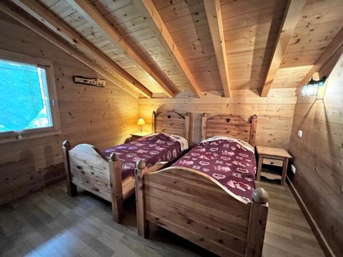two beds in a room with wooden walls at Aulp de Suz 2 - Chalet avec vue in La Clusaz