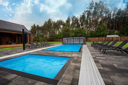 a patio with two pools and chairs and trees at Złota Szyszka Radawa in Radawa