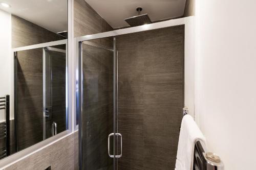 a shower with a glass door in a bathroom at Spacious 4 bedrooms flat in New Oxford Street in London