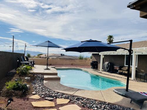 ein Pool mit zwei Sonnenschirmen im Hof in der Unterkunft Welcome to Casa Azul Havasu, with Pool Spa, new remodel, close to Ohv access in Lake Havasu City