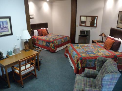 a hotel room with two beds and a desk at RiverBank Lodge in Petersburg