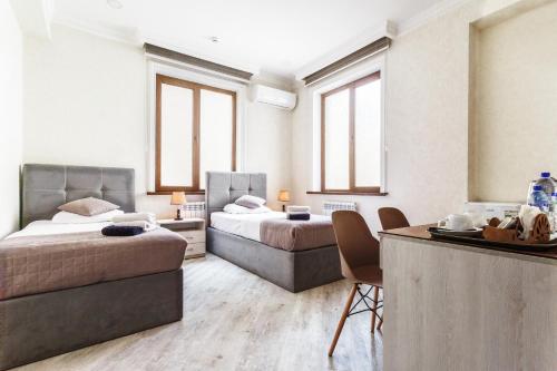een slaapkamer met 2 bedden en een tafel met stoelen bij ELDI Hotel in Tasjkent