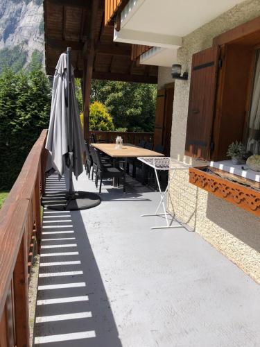 a patio with an umbrella and a table with chairs at Le Chalet Carpe Diem in Le Bourg-dʼOisans