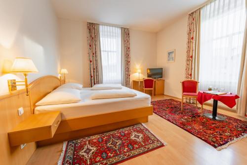 a bedroom with a large bed and a red rug at Postwirt in Seeboden