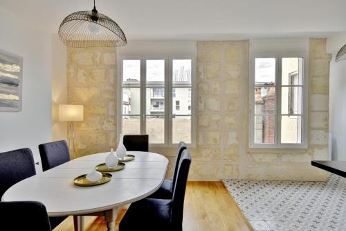 une salle à manger avec une table et des chaises blanches dans l'établissement L'Entre Deux - Magnifique T3 quartier Saint Michel, à Bordeaux