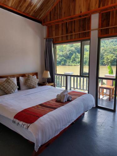 a bedroom with a large bed with a large window at Nam ou view villa in Nongkhiaw