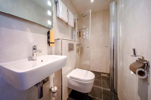 a bathroom with a sink and a toilet and a shower at OZO Hotels Cordial Amsterdam in Amsterdam