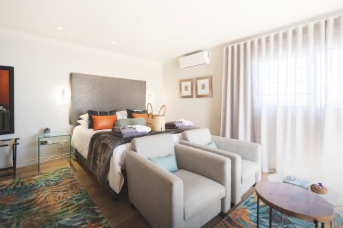 a bedroom with a bed and a couch and a chair at Beach Villa Wilderness in Wilderness