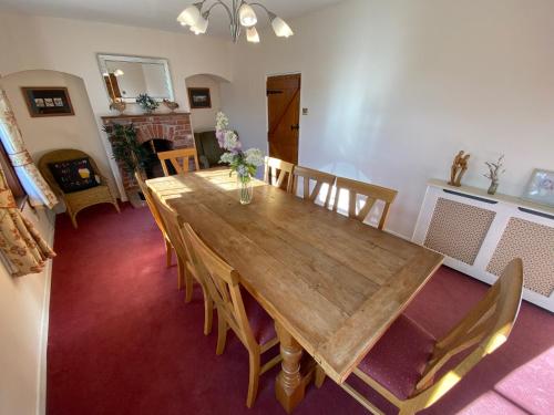 een eetkamer met een houten tafel en stoelen bij Carlton Cottage Country Retreat - Perfect for Ipswich - Aldeburgh - Southwold - Thorpeness - Sizewell B - Sizewell C - Sleeps 13 in Little Glenham