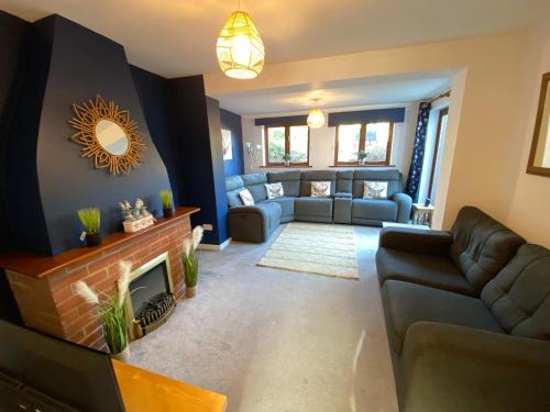 een woonkamer met een bank en een open haard bij Carlton Cottage Country Retreat - Perfect for Ipswich - Aldeburgh - Southwold - Thorpeness - Sizewell B - Sizewell C - Sleeps 13 in Little Glenham
