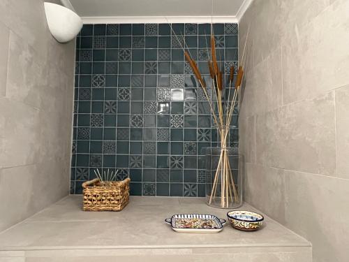 baño con azulejos verdes y cestas en un estante en A Casa Branca, en Mértola