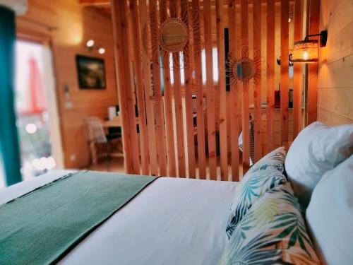 a bedroom with a bed with a wooden head board at Les Lodges de la ViaRhôna / cabane-spa in Virignin