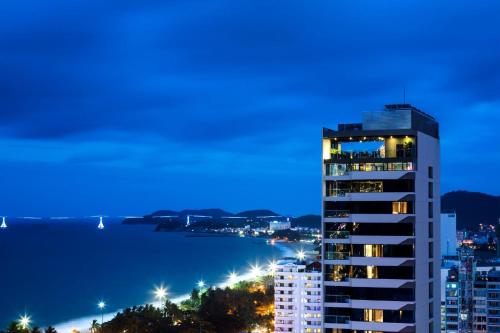 a night view of a city with a tall building at Alana Nha Trang Beach Hotel in Nha Trang
