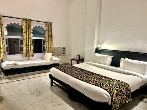 a bedroom with a large bed and two windows at Hotel The Tiger in Udaipur