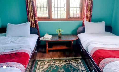 two beds in a room with a table between them at Patlekhet Eco Farmhouse in Dhulikhel