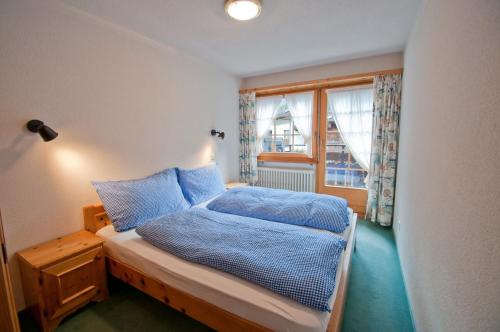a bedroom with a bed with blue sheets and a window at Dent Blanche in Zermatt