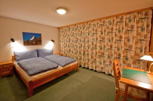 a bedroom with a bed with a curtain and a desk at Dent Blanche in Zermatt