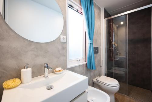 a bathroom with a sink and a toilet and a mirror at Dune Prestige & Chalets in Bibione