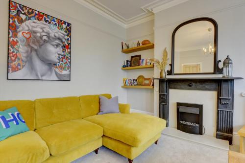 a living room with a yellow couch and a fireplace at Stylish 2 Bedroom Maisonette With Parking in Harrogate