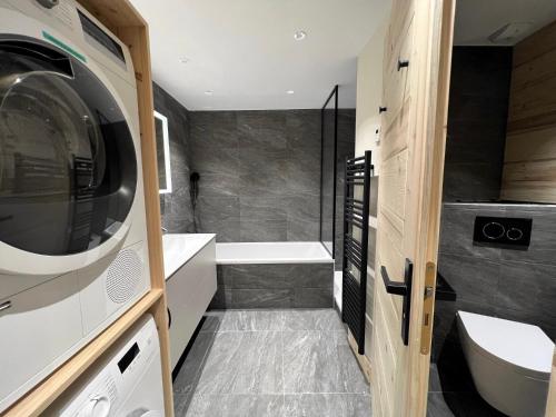 a bathroom with a washer and dryer next to a tub at POLARIS Bel appartement village et pistes in La Clusaz