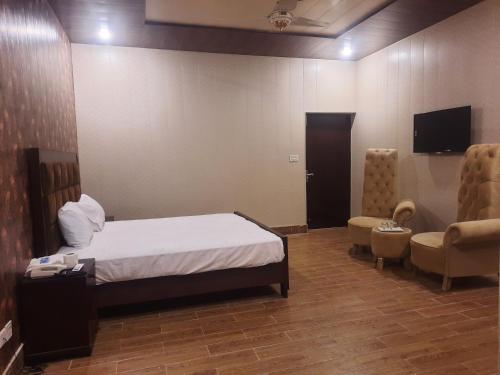 - une chambre avec un lit, une télévision et une chaise dans l'établissement Royal Fort Executive Hotel Gulberg, à Lahore