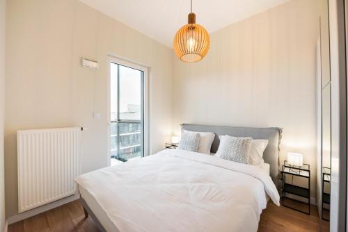 a white bedroom with a large bed and a window at Wola Lush Apartment in Warsaw