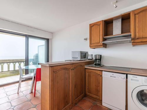 une cuisine avec un four micro-ondes et une table avec une fenêtre dans l'établissement Appartement moderne en bord de mer avec balcon et parking - FR-1-2-306, à Hendaye