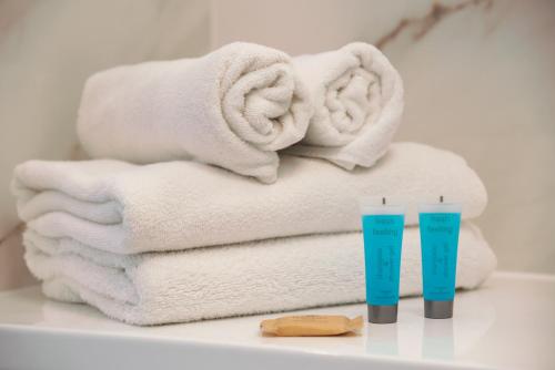 a pile of towels and two plastic cups on a shelf at Wola Lush Apartment in Warsaw