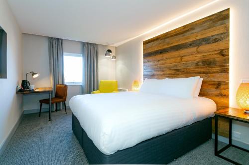 a hotel room with a large bed and a desk at Clarion Cedar Court Wakefield Hotel in Wakefield