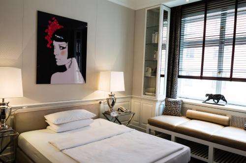 a bedroom with a bed and a couch and a window at Hotel Opera in Munich