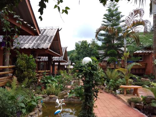 a garden in front of a building with a pond at Lung Soi Nguen Homstay Pang Oung in Pang Ung