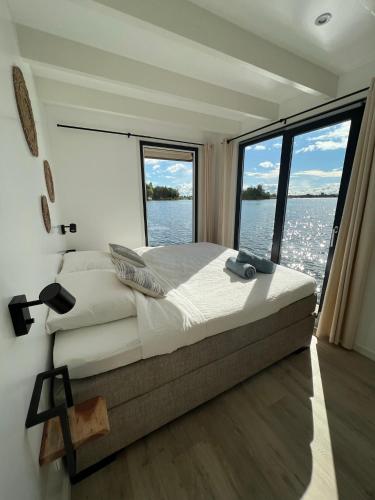 a bedroom with a large bed and a large window at Surla houseboat "Aqua Zen" Kagerplassen with tender in Kaag