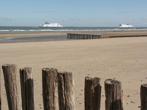 a wooden fence on the beach with two ships in the ocean at Flobart grand appartement à Sangatte au rdc et à 30 metres de la plage in Sangatte