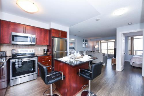 a kitchen with wooden cabinets and a kitchen island with bar chairs at PlanURstay - 310 Burnhamthorpe Road West in Mississauga