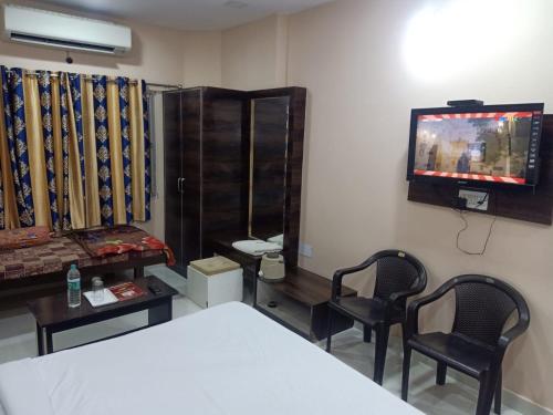 a room with a bed and two chairs and a tv at Laxmi Mahal in Udaipur