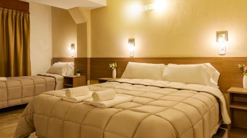 Una cama grande en una habitación de hotel con toallas. en Wooden Hotel en Villa Carlos Paz