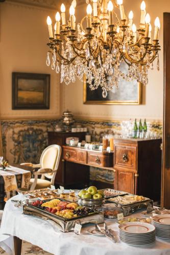 ein Esszimmer mit einem Tisch mit Essen und einem Kronleuchter in der Unterkunft Estoril Vintage Hotel in Estoril