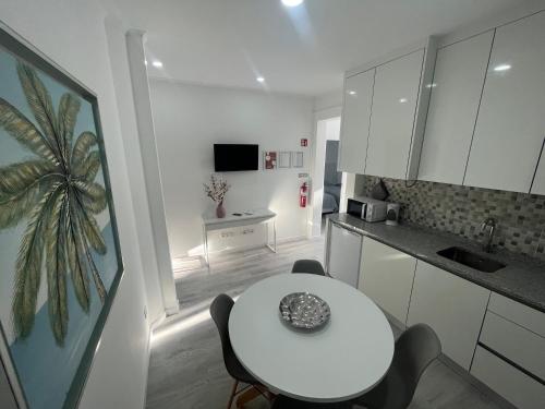 une cuisine avec une table blanche, une table et des chaises dans l'établissement Lisbon Ocean Apartments, à Costa da Caparica