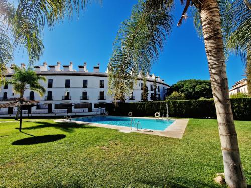 a large white building with a swimming pool and palm trees at Velez Nazari in Vélez de Benaudalla